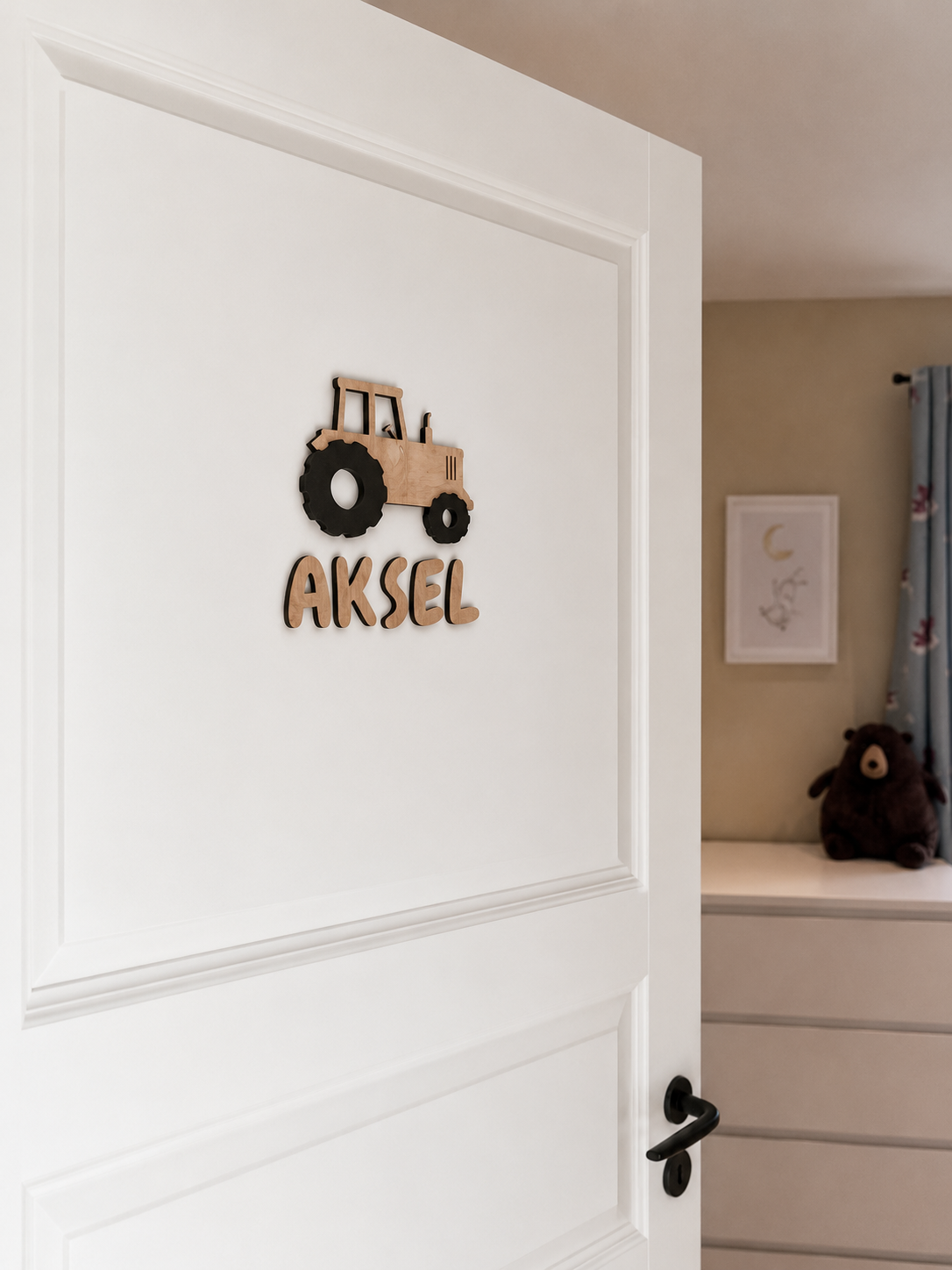 Et personlig navneskilt med traktor som henger på en barneromsdør med navnet Aksel.