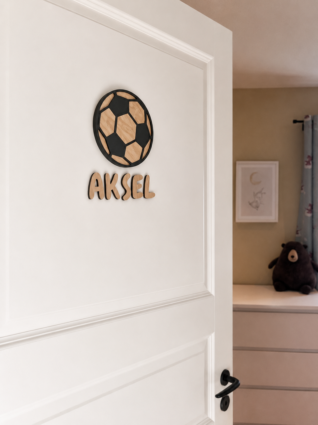 Navneskilt til barnerom med en håndlaget fotball som henger over barnets navn.