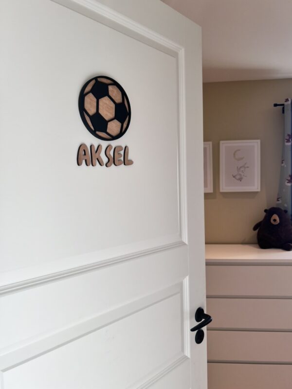 Navneskilt til barnerom med en håndlaget fotball som henger over barnets navn.