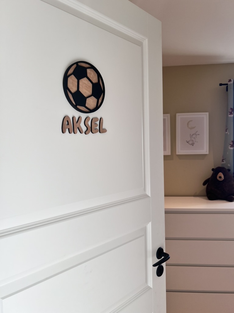 Navneskilt til barnerom med en håndlaget fotball som henger over barnets navn.