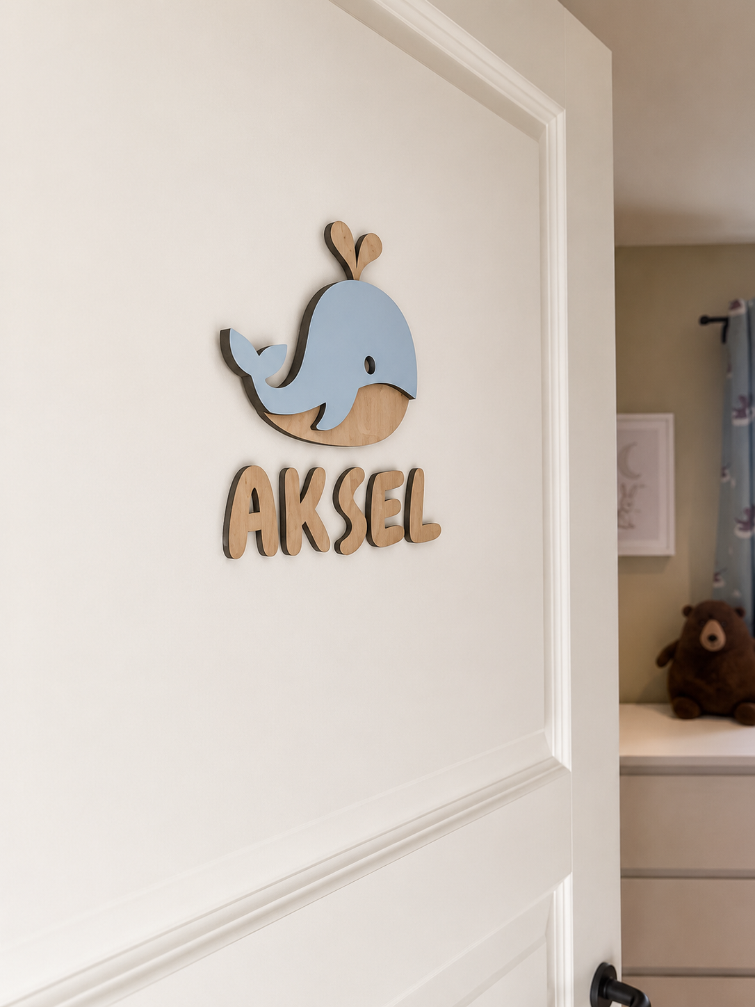 Navneskilt til barnerom med en håndlaget hval som henger over barnets navn.