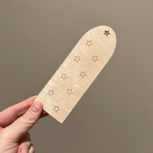 Baksiden av personlig bokmerke med astronaut og navn, bak finner man lasergraverte stjerner.