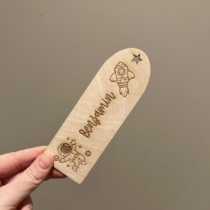 Personlig lasergravert bokmerke i 3 mm bjørkefiner med astronaut, rakett, stjerner og barnets navn, perfekt for barn som liker å lese.