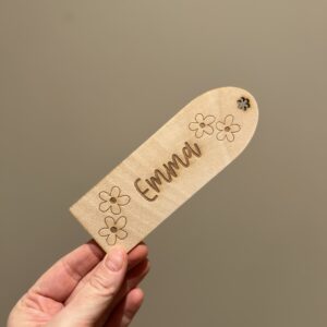 Personlig lasergravert bokmerke i 3 mm bjørkefiner med blomster og barnets navn, perfekt for barn som liker å lese.