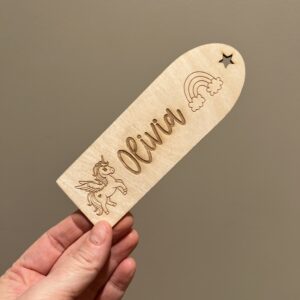 Personlig lasergravert bokmerke i 3 mm bjørkefiner med enhjørning, stjerner, skyer og barnets navn, perfekt for barn som liker å lese.
