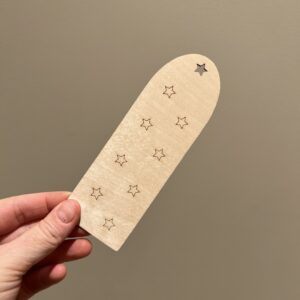 Baksiden av personlig bokmerke med enhjørning og navn, bak finner man lasergraverte stjerner.