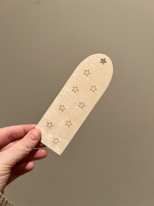 Baksiden av personlig bokmerke med enhjørning og navn, bak finner man lasergraverte stjerner.