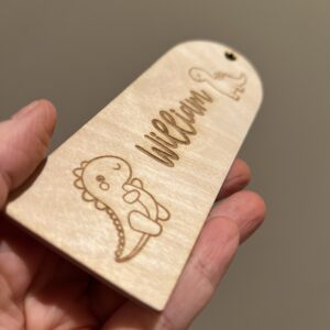 Detaljer av et personlig bokmerke med lasergraverte dinosaurer og valgfritt navn.