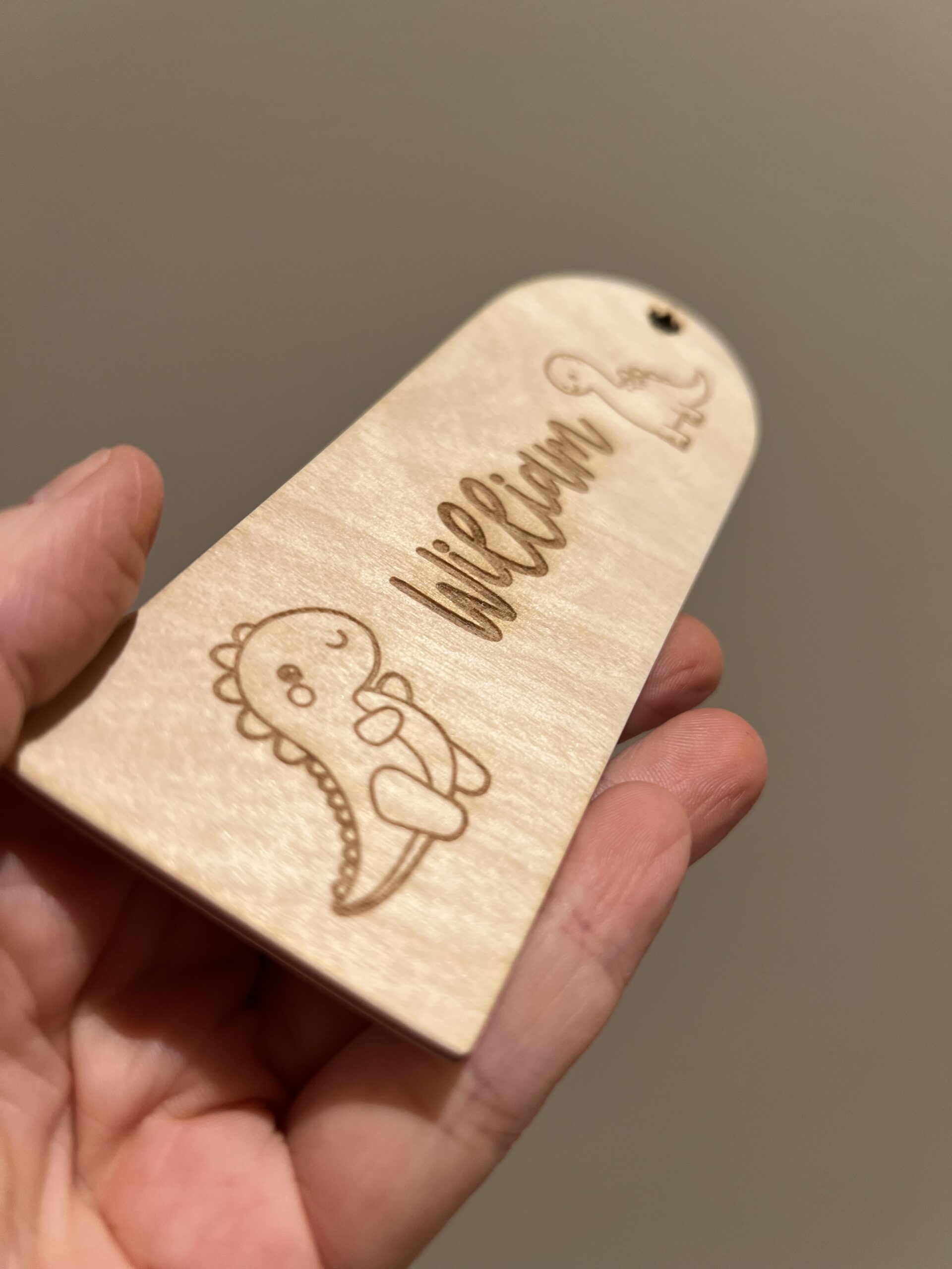 Detaljer av et personlig bokmerke med lasergraverte dinosaurer og valgfritt navn.