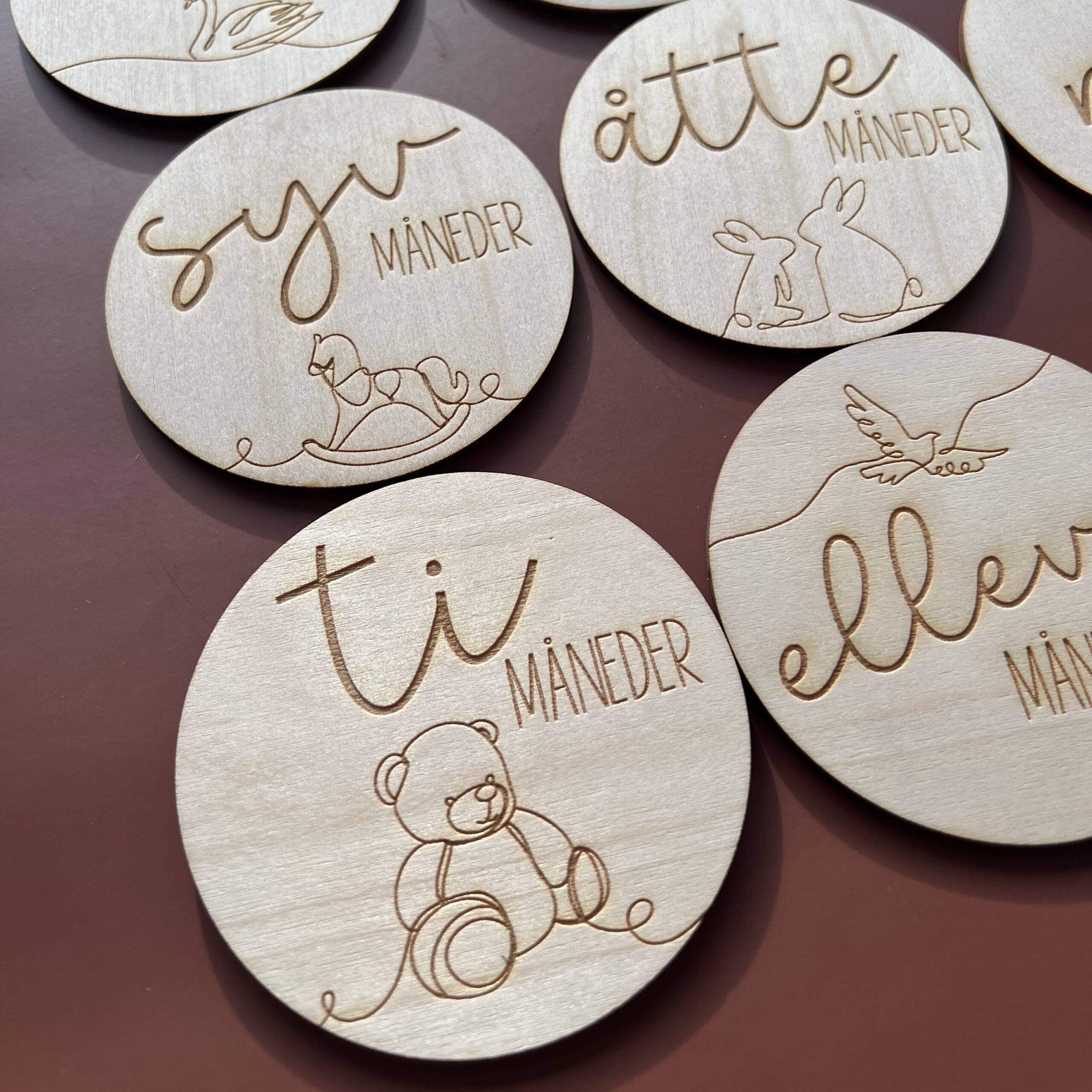 Detaljbilde av milepælskort i tre med lasergravert illustrasjon og norsk tekst.