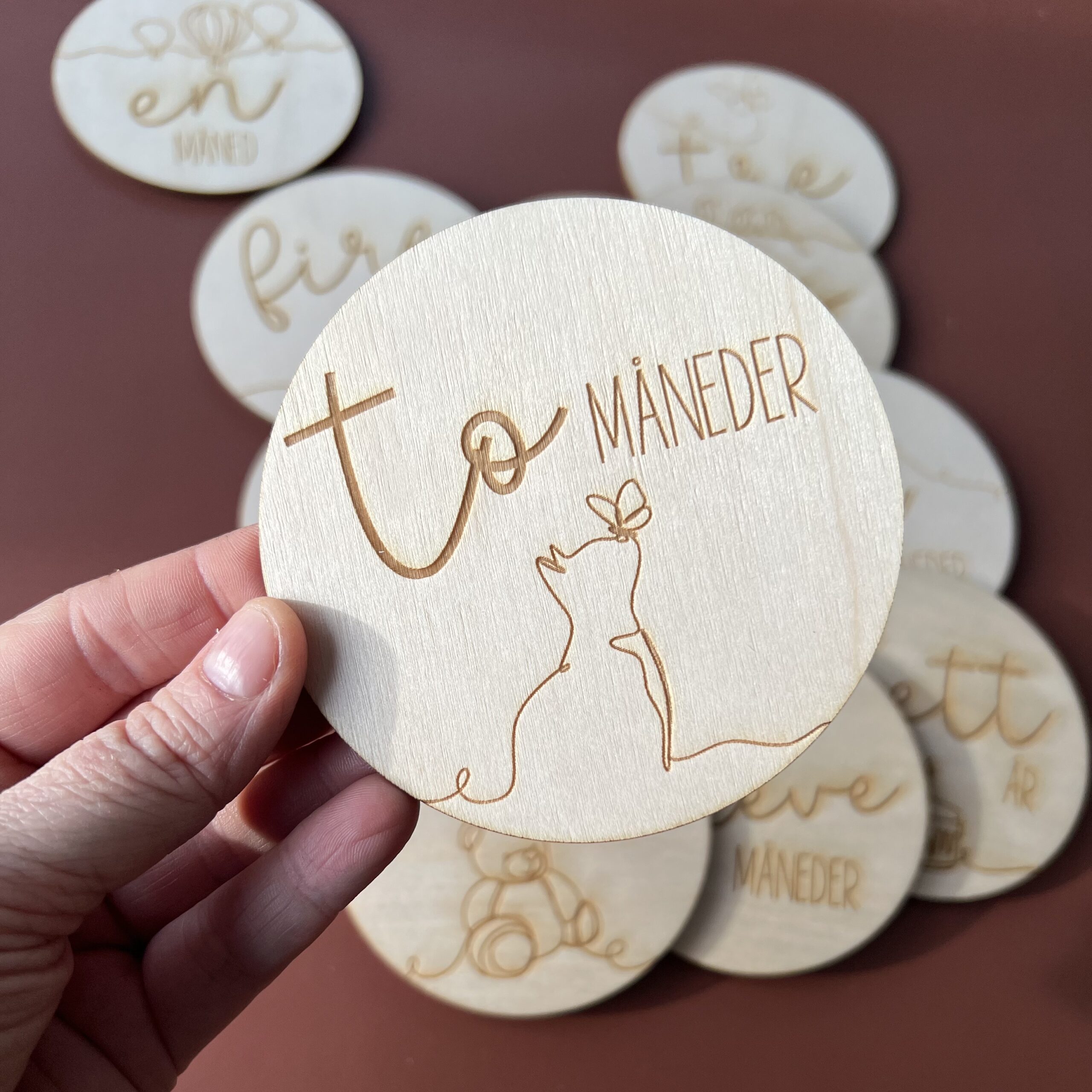 En closeup av en av milepælskortene - her ser du "to måneder" sammen med en lasergravert katt med sommerfugl på nesen.