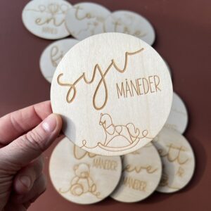 En closeup av en av milepælskortene - her ser du "syv måneder" sammen med en lasergravert gyngehest.
