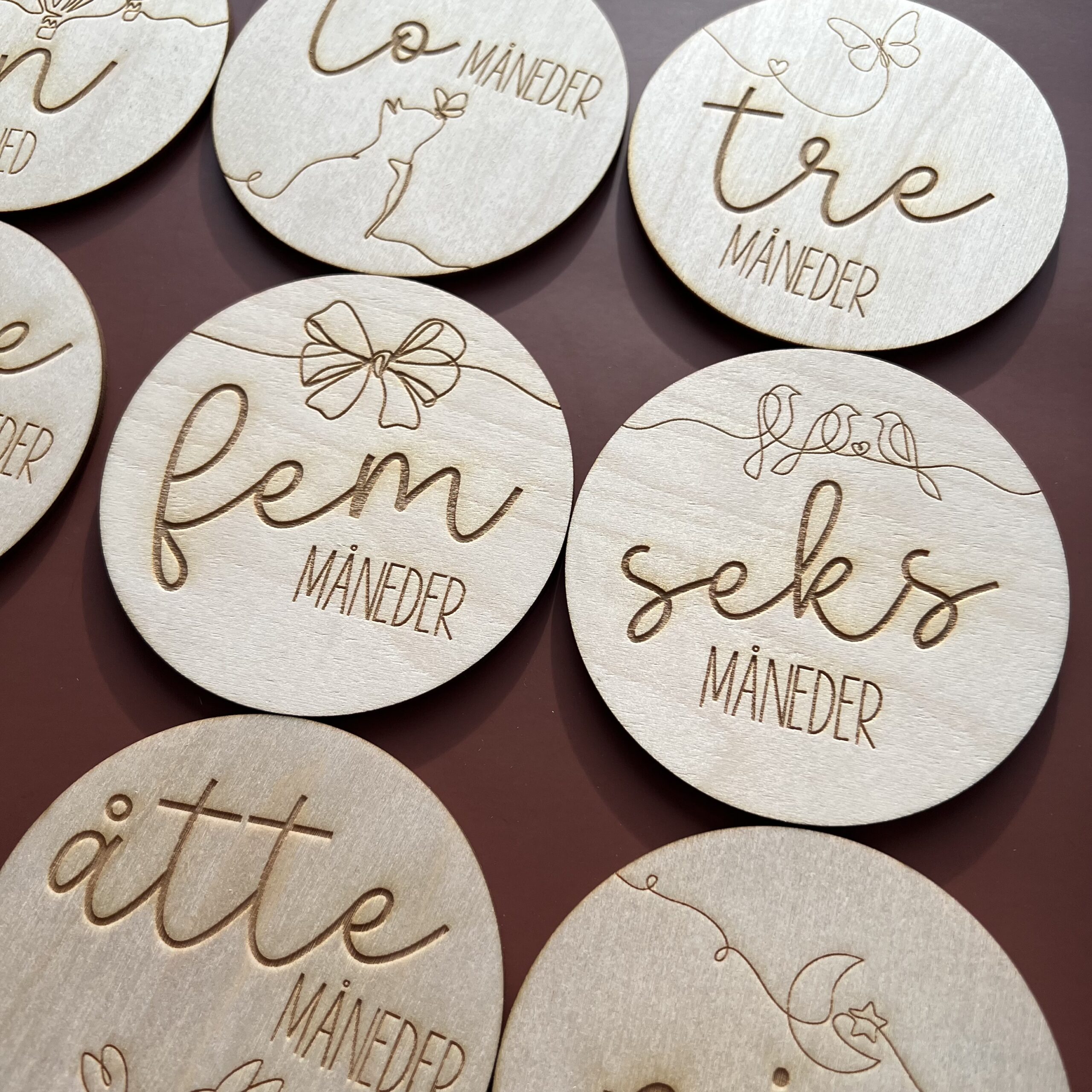 Detaljbilde av milepælskort i tre med lasergravert illustrasjon og norsk tekst.