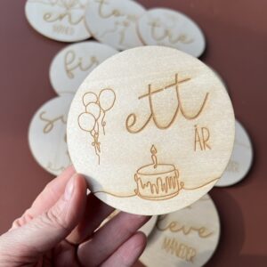 En closeup av en av milepælskortene - her ser du "ett år" sammen med lasergraverte ballonger og en kake.