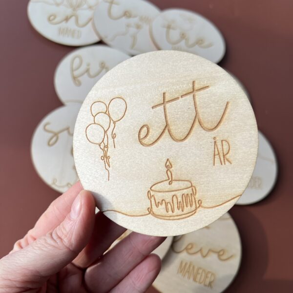 En closeup av en av milepælskortene - her ser du "ett år" sammen med lasergraverte ballonger og en kake.