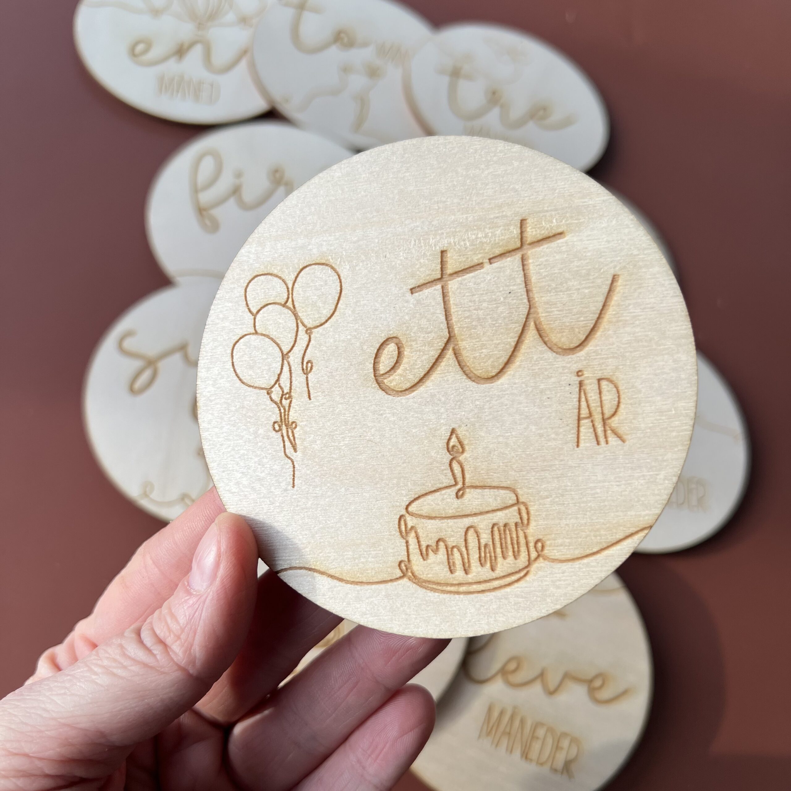 En closeup av en av milepælskortene - her ser du "ett år" sammen med lasergraverte ballonger og en kake.