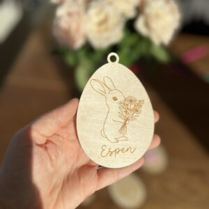 Personlig påskeornament i bjørkfiner, oval form med lasergravert kanin og blomster, med valgfritt navn eller tekst.