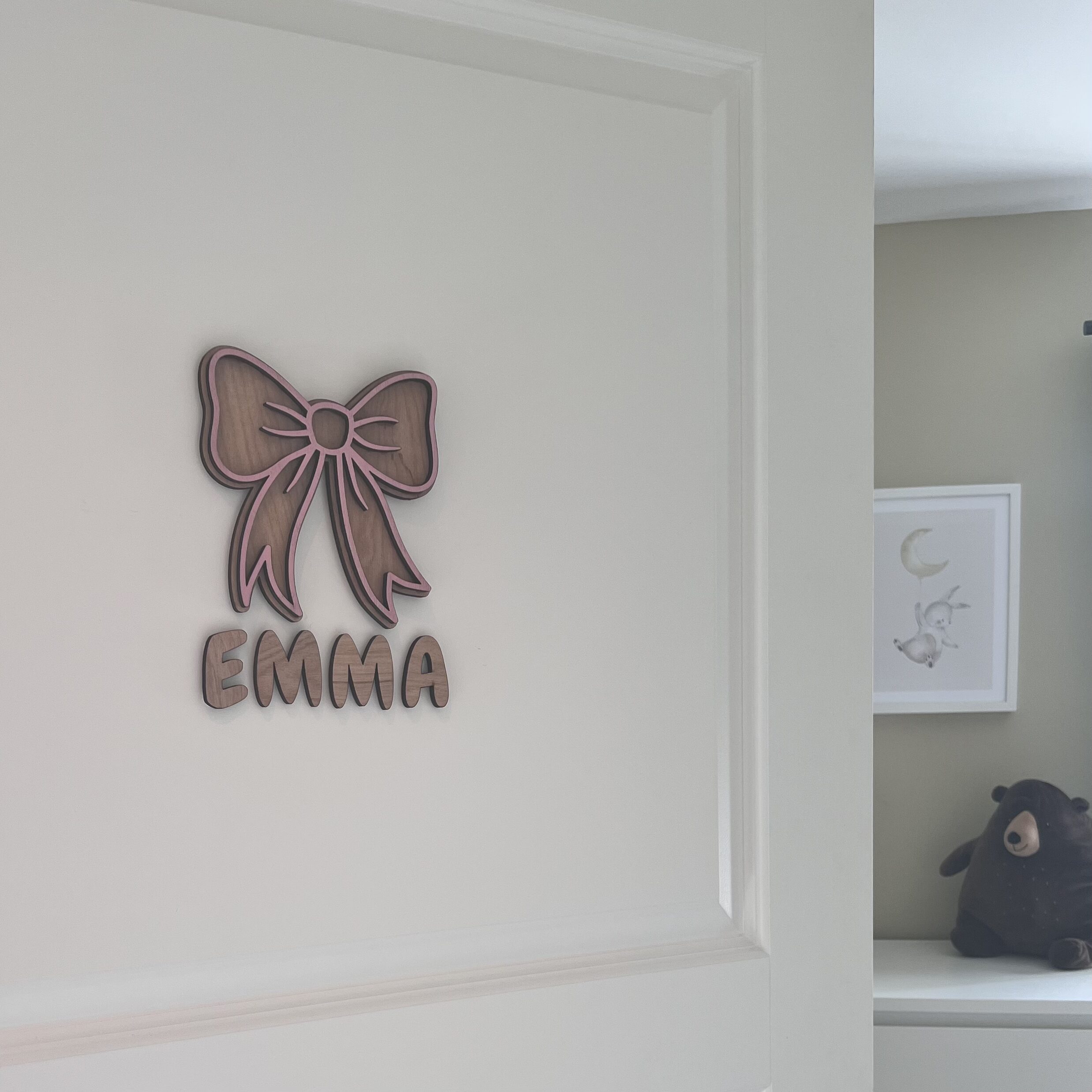 Håndlaget navneskilt med barnets navn og en rosa sløyfe i bjørkfiner fra ByRossland, perfekt til barnerom eller babyrom.