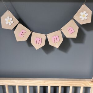 Personlig girlander med navn i rosa akryl til barnerommet med to endreflagg med hvite blomster.