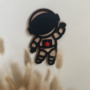 En håndlaget astronaut veggfigur i bjørkfiner henger på veggen. Denne passer til barnerommet til de som er glad i verdensrommet.