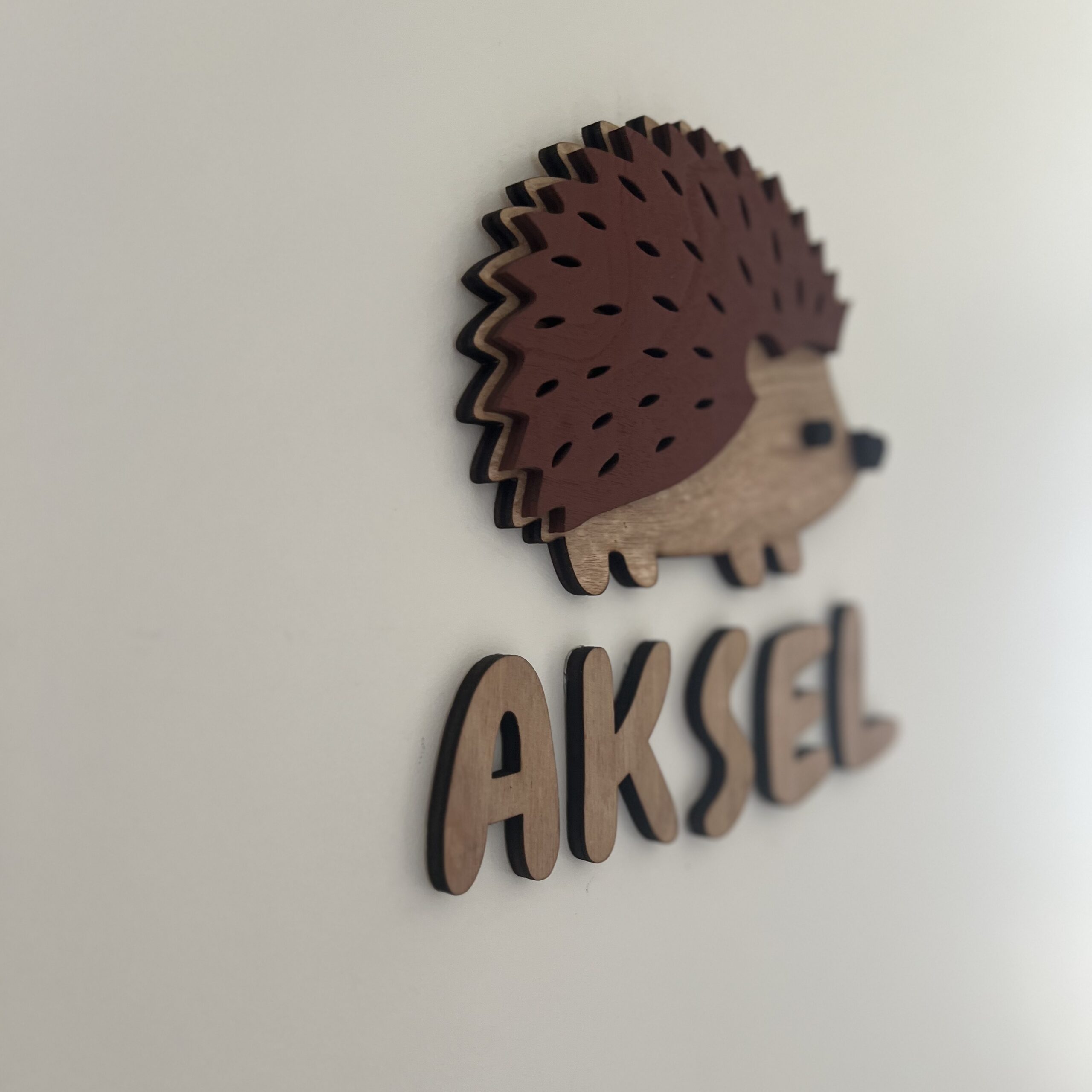 Et personlig navneskilt med Aksel som er håndlaget av ByRossland i Bergen - perfekt for barneromsdøren!