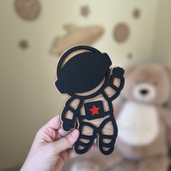 En håndlaget astronaut veggfigur holdes opp på barnerommet.