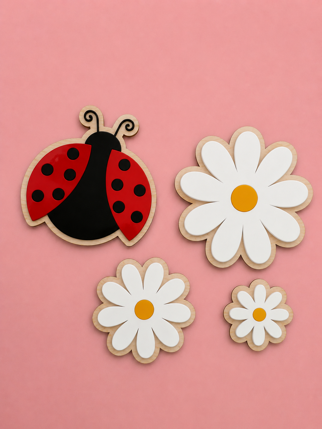Veggdekorasjon til barnerommet laget i bjørkfiner og akryl. Her ser du en marihøne og tre blomster på en rosa bakgrunn.
