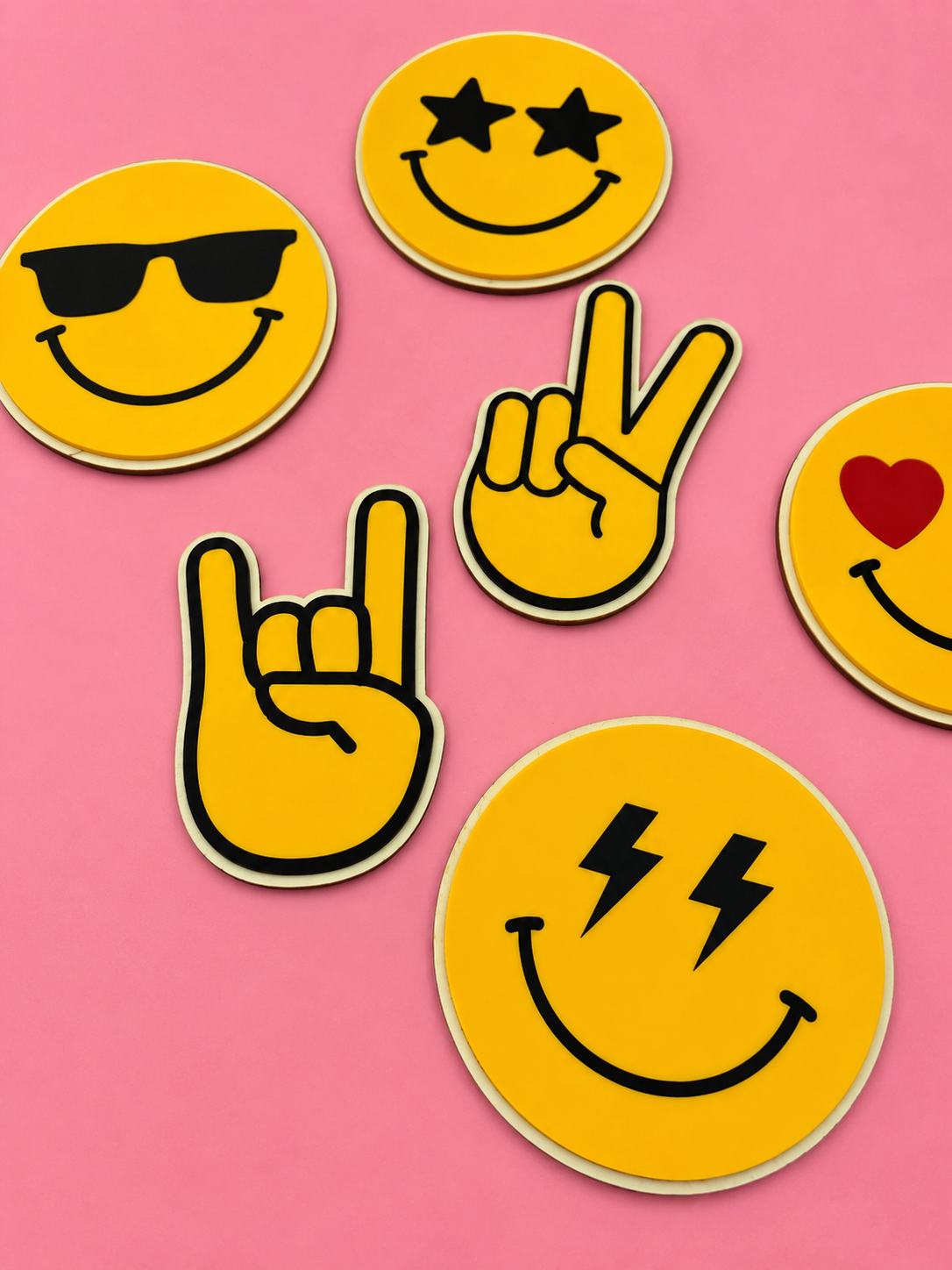 Gule emoji-klistremerker med solbriller, stjerne-øyne, hjerte, lyn-øyne og håndtegn på rosa bakgrunn
